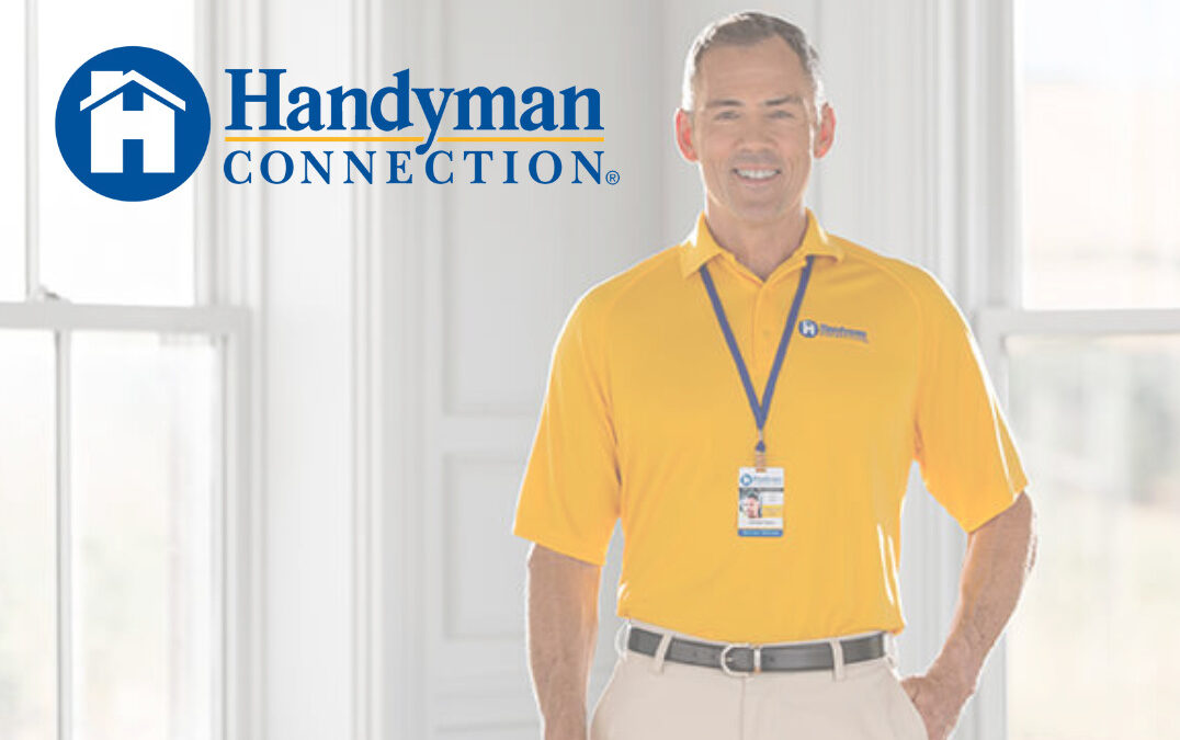 Man in a yellow Handyman Connection polo in a living room with the Handyman Connection logo to his left.