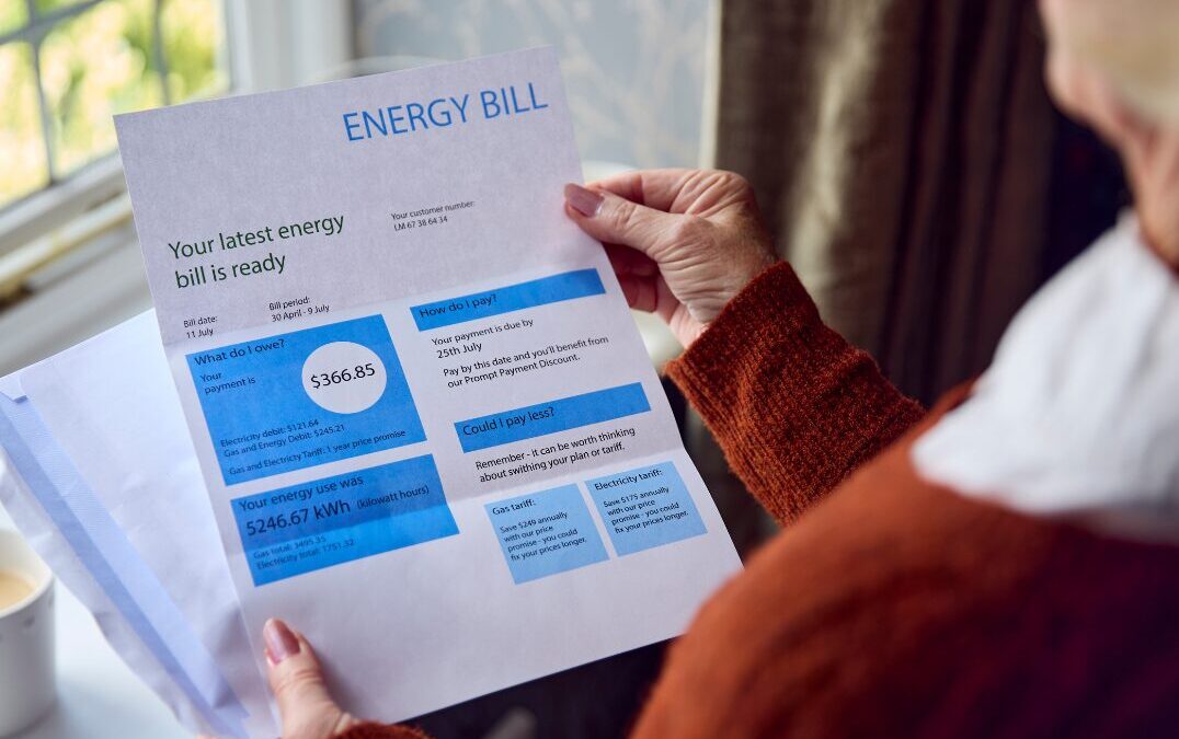 Person holding an energy bill showing a total due of $366.85 and energy use of 5246.67 kWh.